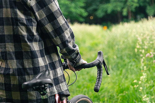 A cyclist walking their bike through a meadow