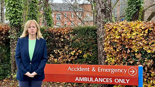 Liz Jarvis stand infront of Royal Hampshire County Hospital Accident and Emergency sign